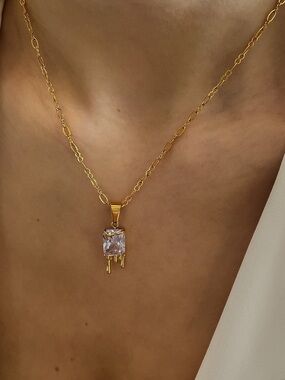 Gold tone stainless steel necklace with clear crystal pendant.